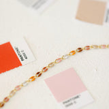 Gold bracelet with colorful beads and Pantone color swatches.