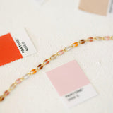 Gold chain bracelet with colorful stones and Pantone color swatches.