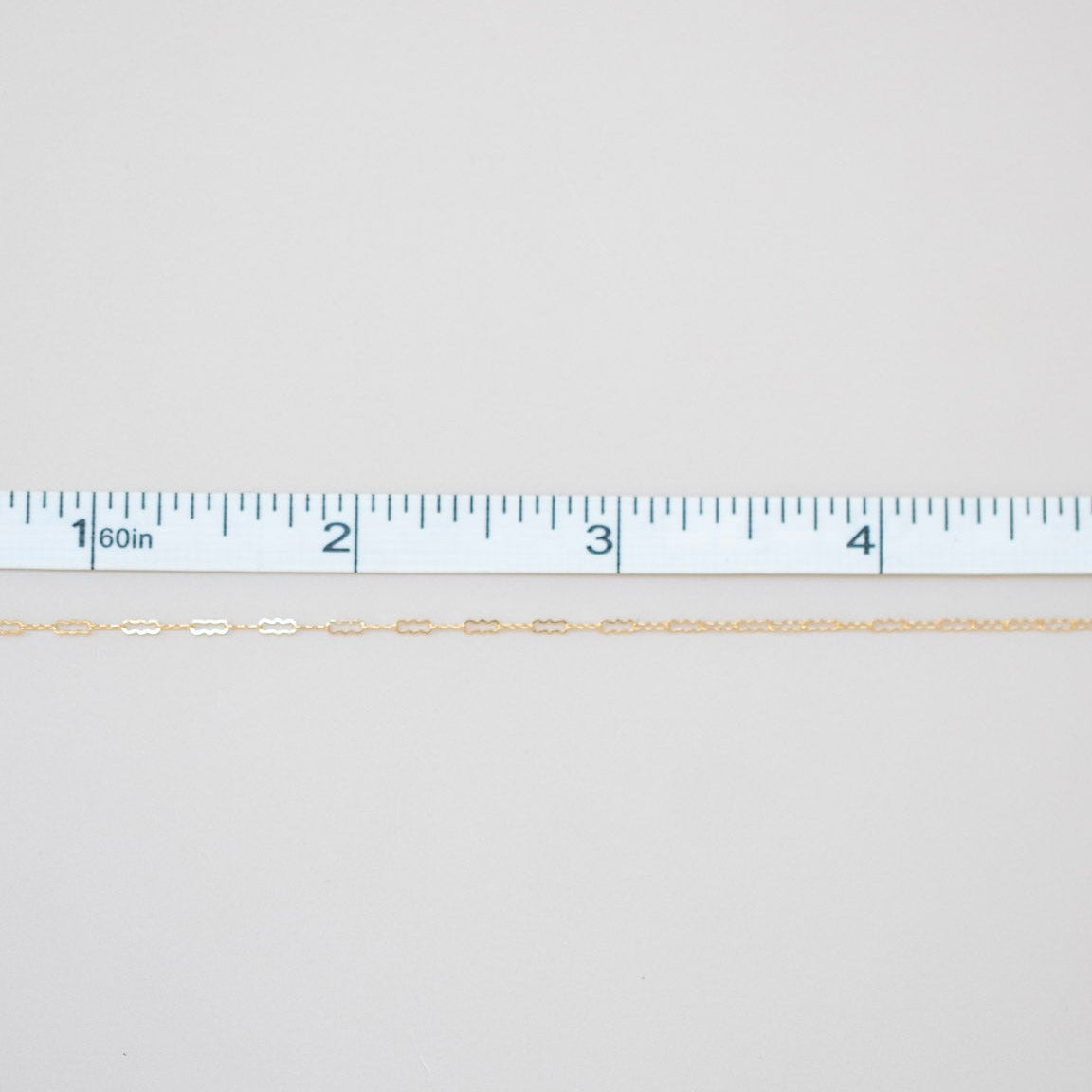 Gold chain with a ruler for scale on a white background