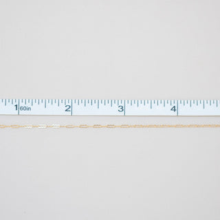 Gold chain with a ruler for scale on a white background