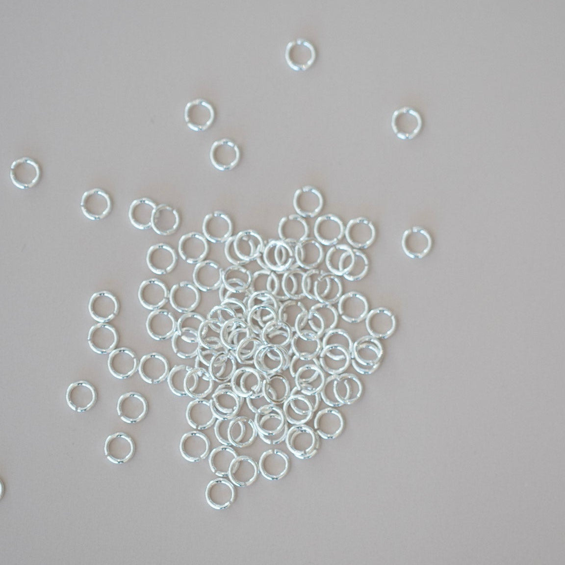 Silver jump rings scattered on a gray background