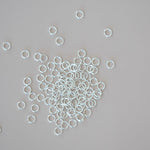 Silver jump rings scattered on a gray background