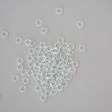 Silver jump rings scattered on a gray background