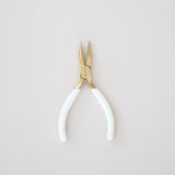 Pair of pliers with white handles on a light gray background