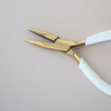 Pair of gold-handled pliers with white handles on a light gray background