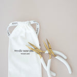 Pair of gold pliers on a white drawstring bag with text on a beige background