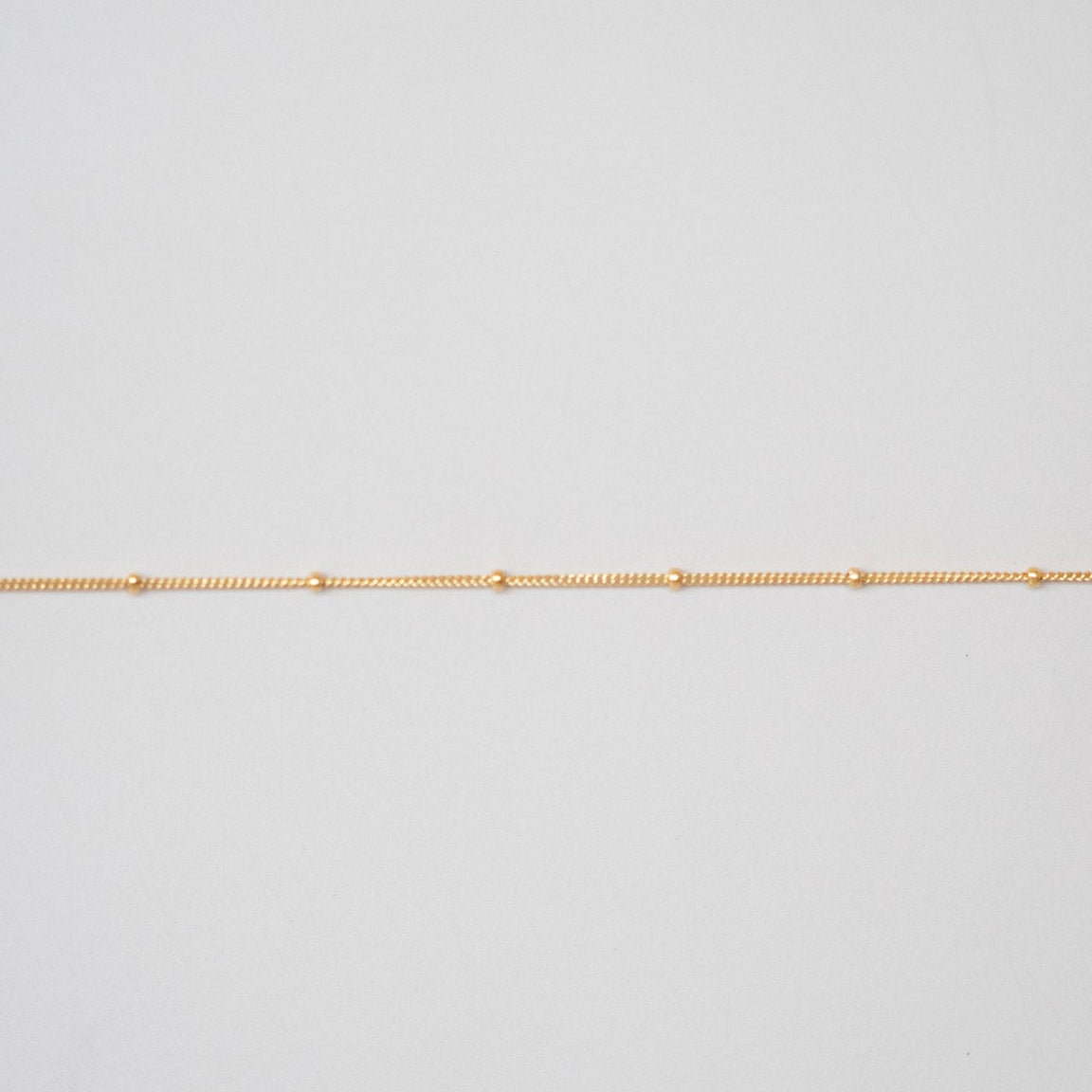 Gold chain on a light gray background
