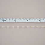 Gold chain with a ruler for scale on a gray background