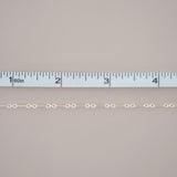 Gold chain with a ruler for scale on a gray background