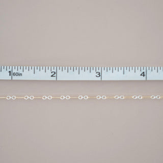 Gold chain with a ruler for scale on a gray background