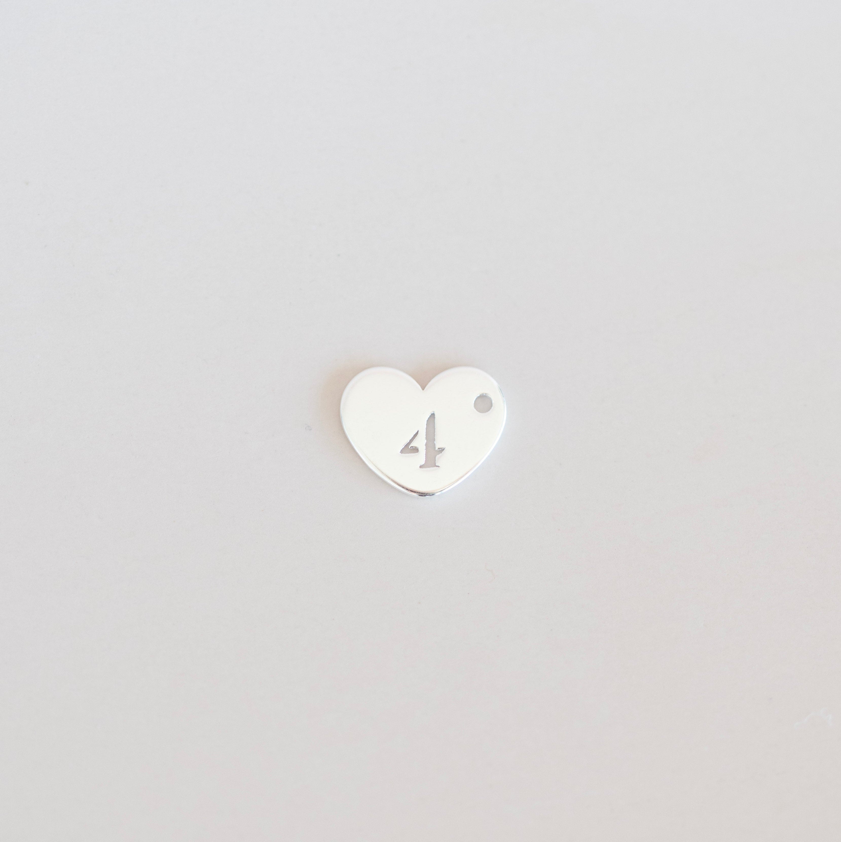 Heart-shaped number '4' charm on a light gray background