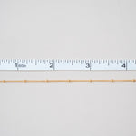 Gold chain next to a ruler on a white background