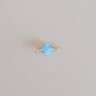 Small blue stone on a thin gold rod against a light gray background