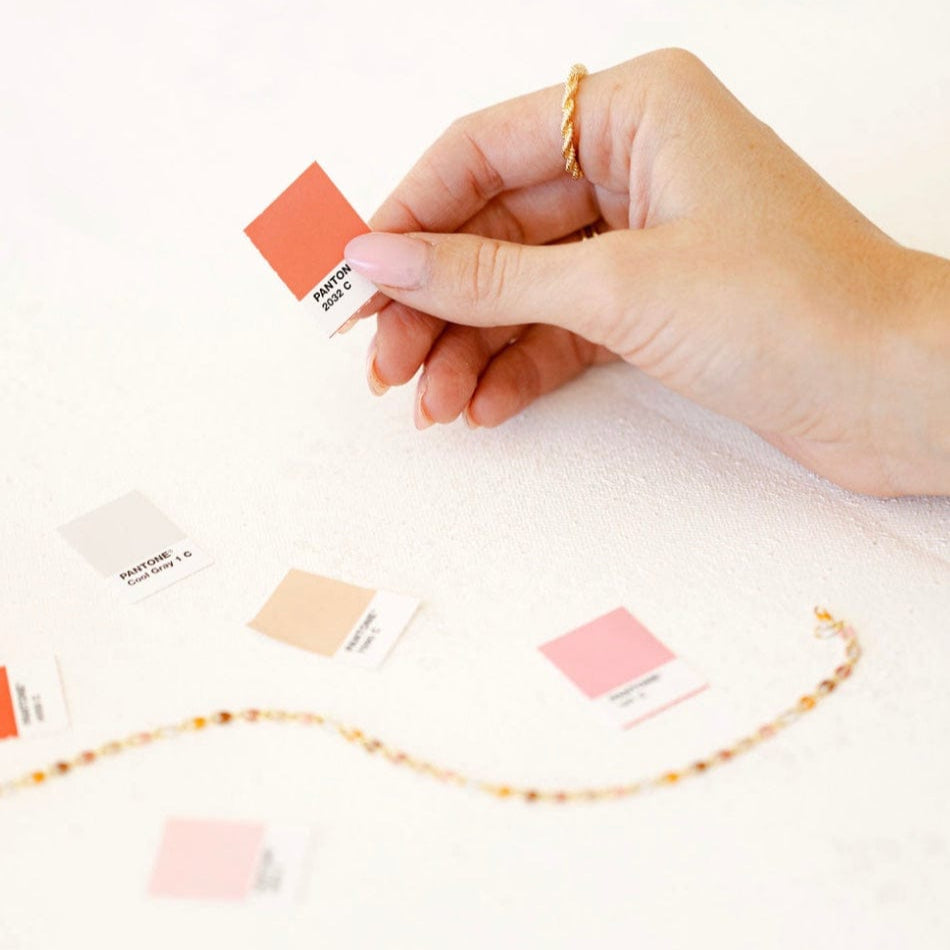 Hand holding coral Pantone swatch card