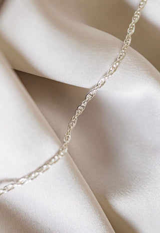 Silver chain necklace on white silk