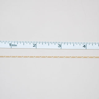 White fabric with a ruler at the bottom for scale on a white background