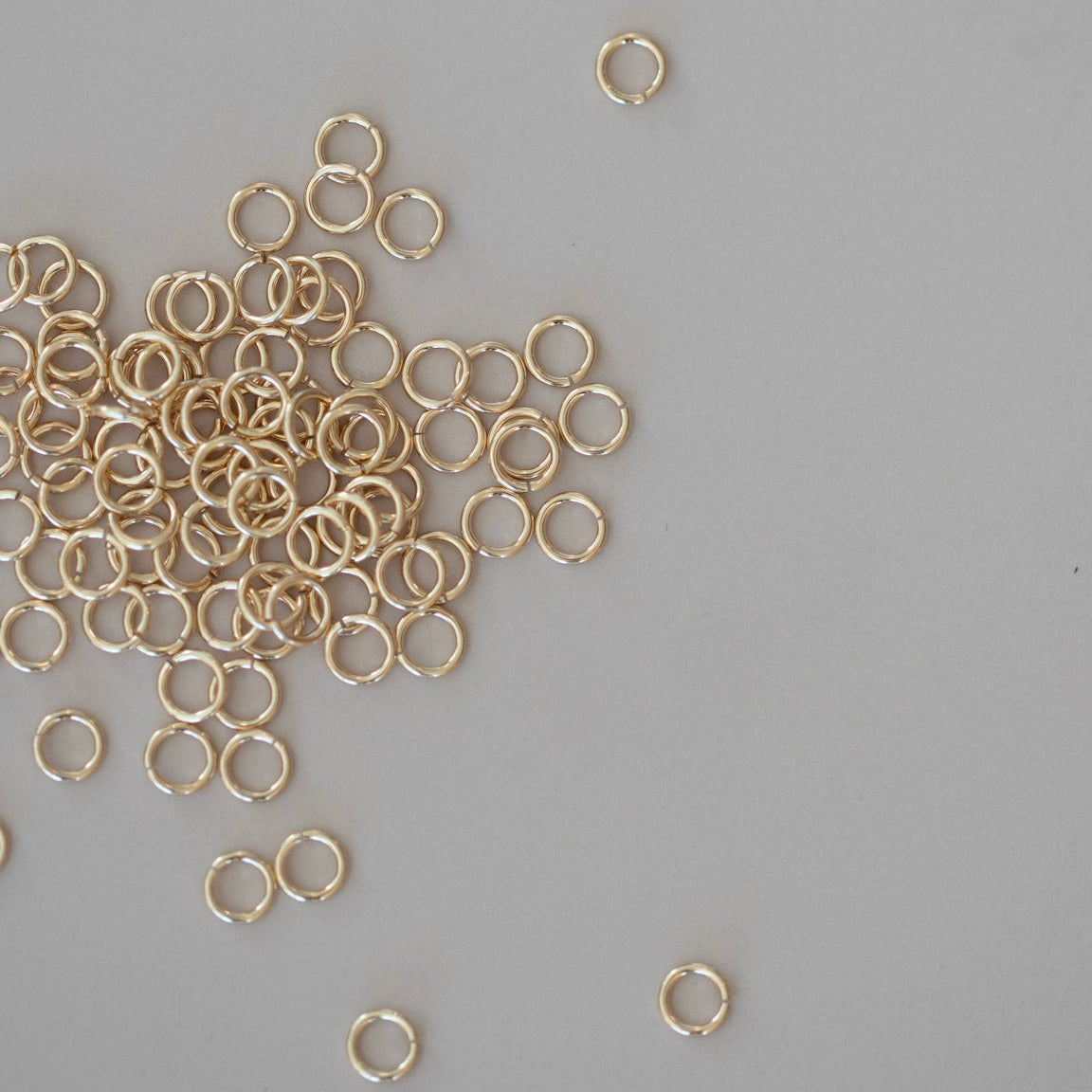 Gold jump rings scattered on a gray background