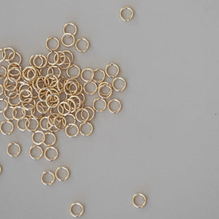 Gold jump rings scattered on a gray background