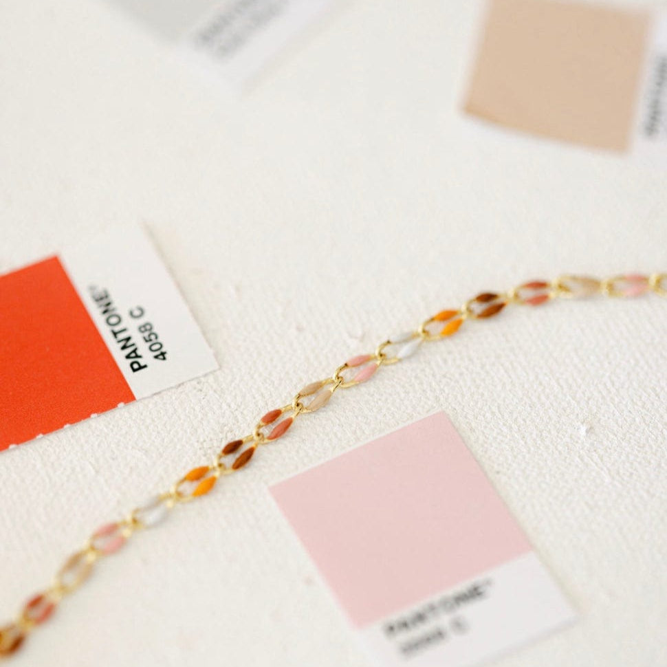Gold bracelet with colorful beads and Pantone color swatches.