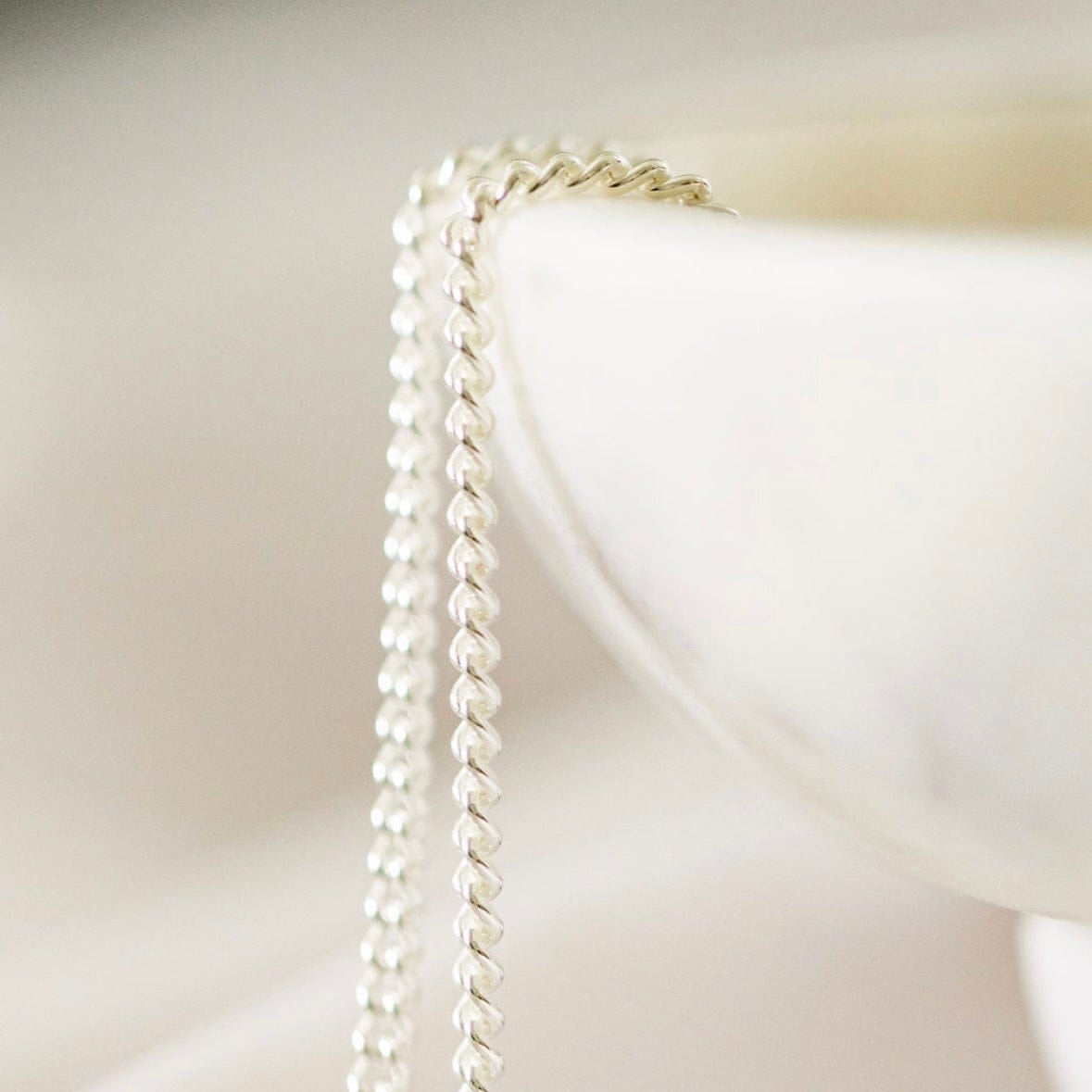 Silver chain draped over a white bowl