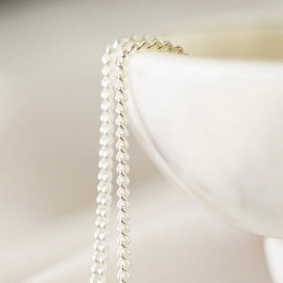 Silver chain draped over a white bowl