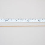 Gold chain with a ruler for scale on a light gray background