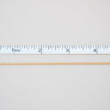 Gold chain with a ruler for scale on a light gray background