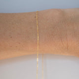 Gold bracelet on a wrist with a plain background