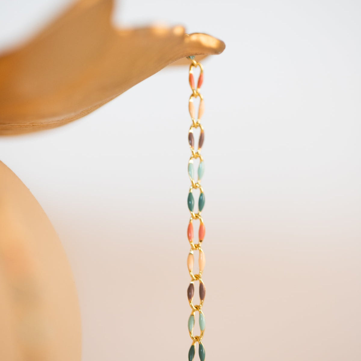 Gold hand holding colorful chain necklace