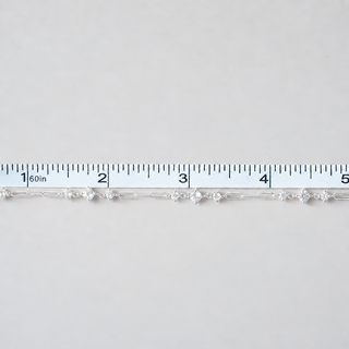 A silver-toned tennis bracelet with clear round-cut gemstones, shown horizontally against a light gray background with a white ruler at the top for scale.