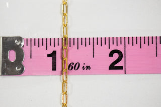 Gold chain measured with pink tape measure, 1-2 inches