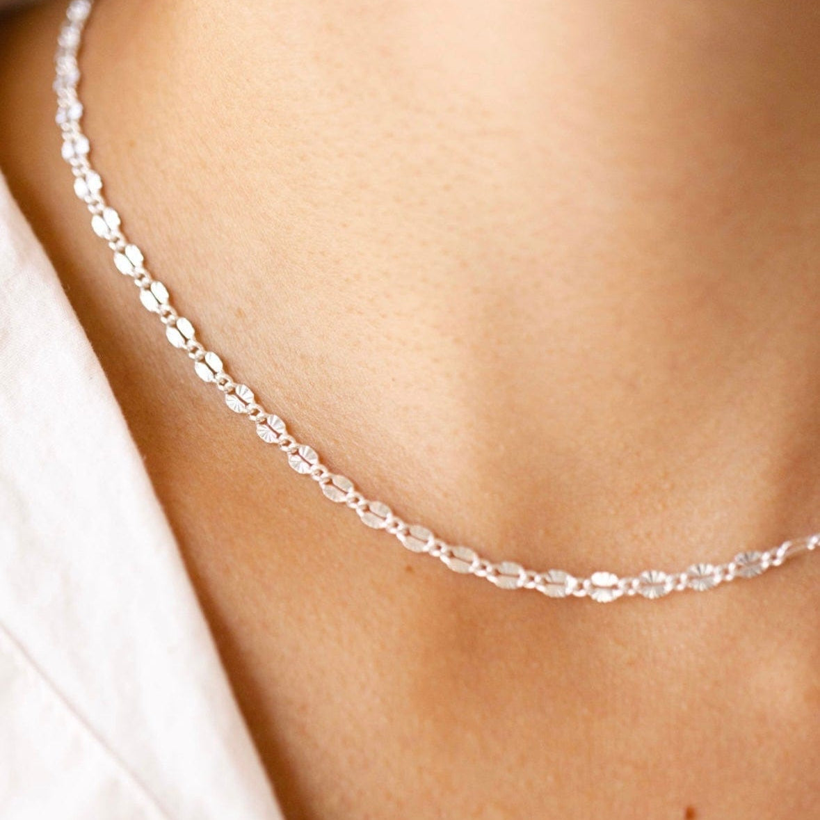 Silver chain necklace on a white shirt
