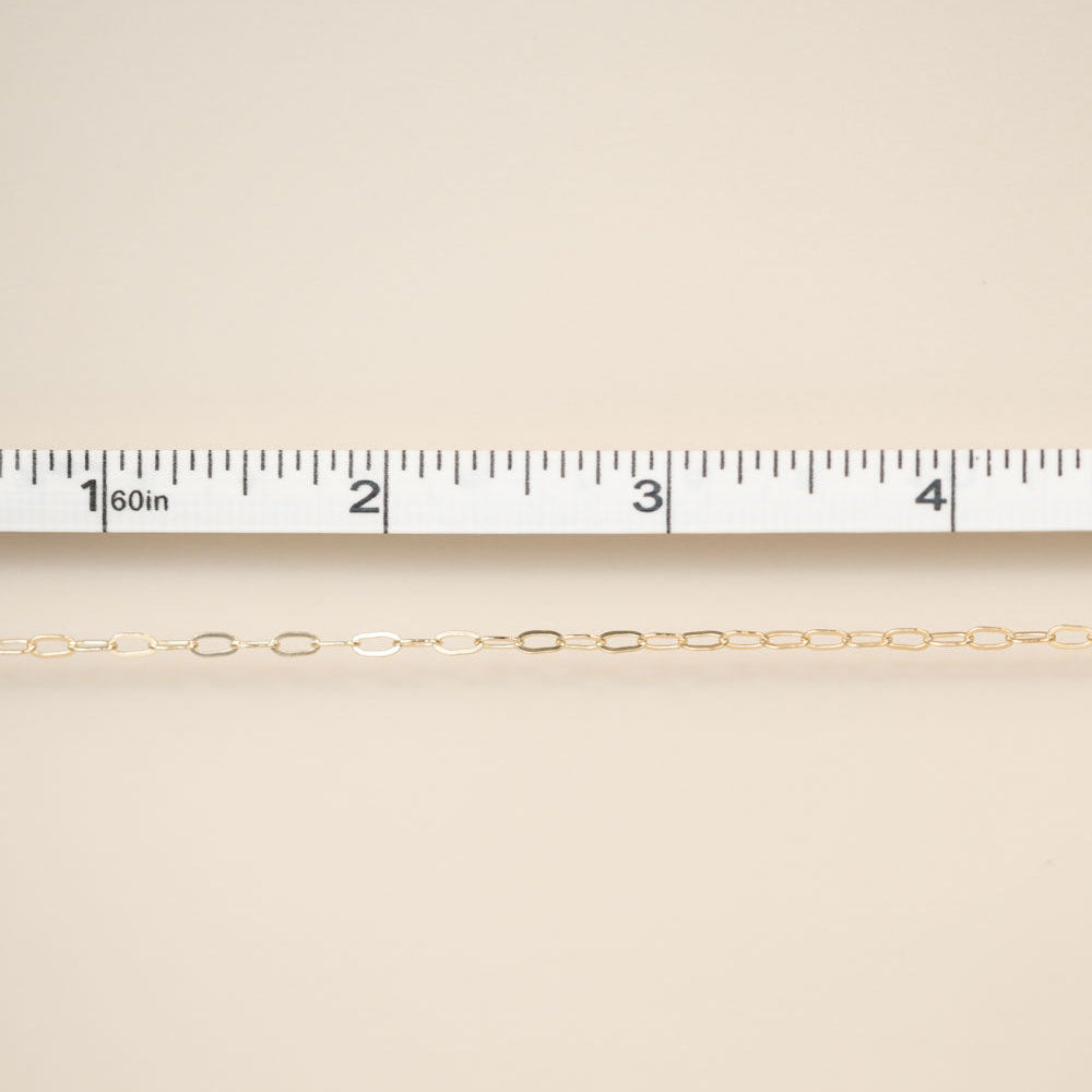 Gold chain on a beige fabric background with a ruler for scale.