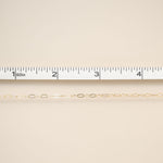 Gold chain on a beige fabric background with a ruler for scale.