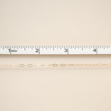Gold chain on a beige fabric background with a ruler for scale.