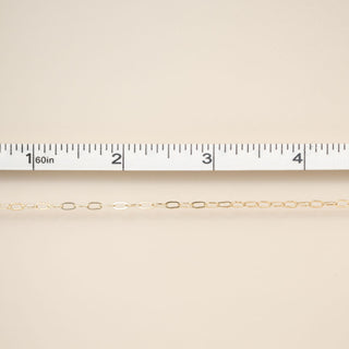 Gold chain on a beige fabric background with a ruler for scale.