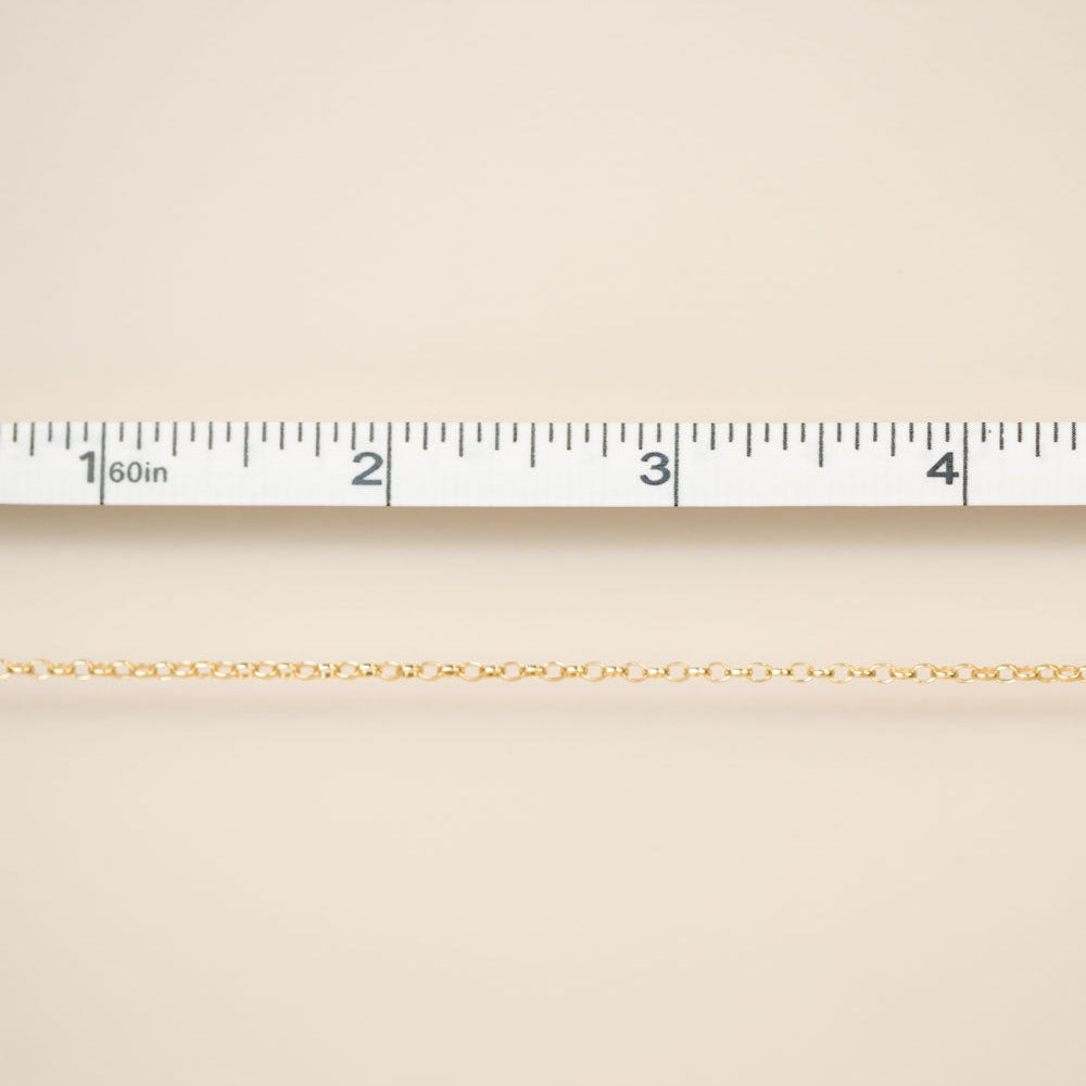 Beige fabric with a gold chain and ruler for scale on a beige background