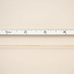 Beige fabric with a gold chain and ruler for scale on a beige background