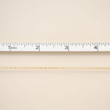 Beige fabric with a gold chain and ruler for scale on a beige background