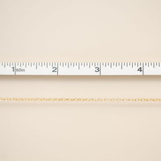 Beige fabric with a gold chain and ruler for scale on a beige background