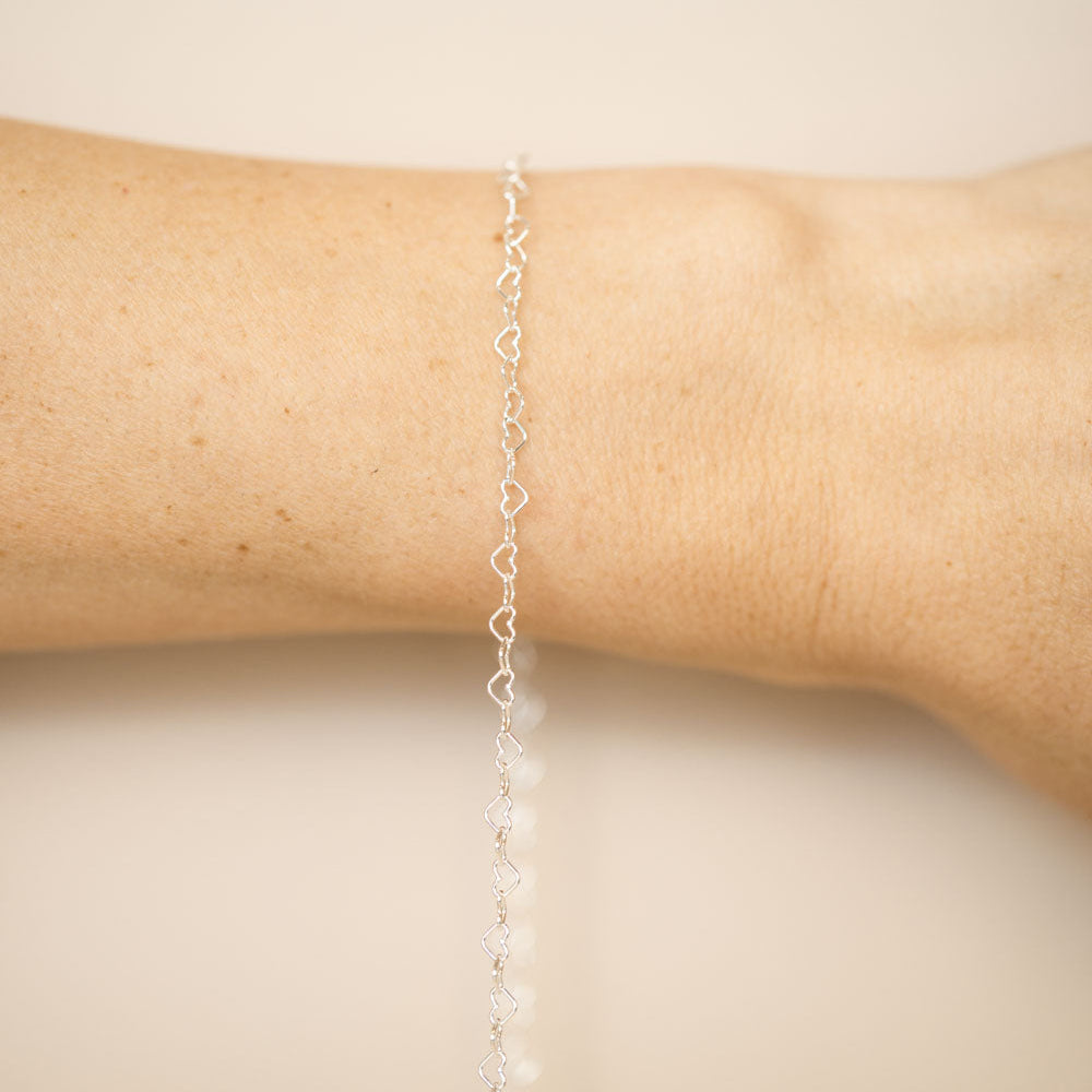 Silver bracelet on a wrist against a beige background