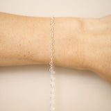 Silver bracelet on a wrist against a beige background