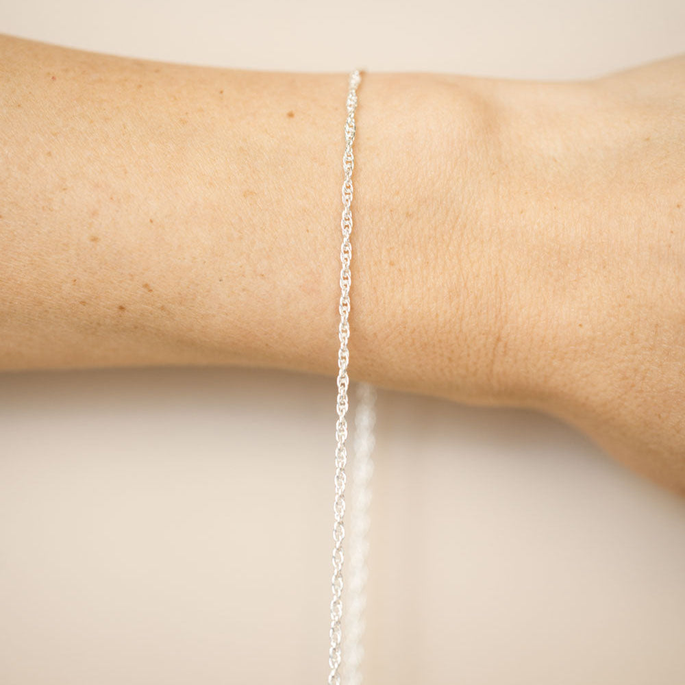 Silver bracelet on a person's wrist against a beige background