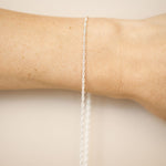 Silver bracelet on a person's wrist against a beige background