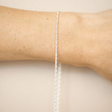 Silver bracelet on a person's wrist against a beige background