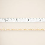Gold chain on a beige background with a ruler for scale