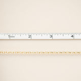 Gold chain on a beige background with a ruler for scale