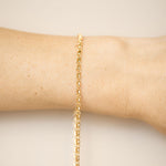 Gold bracelet on a wrist against a beige background