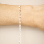 Silver chain bracelet on a wrist against a beige background