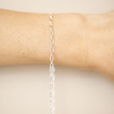 Silver chain bracelet on a wrist against a beige background